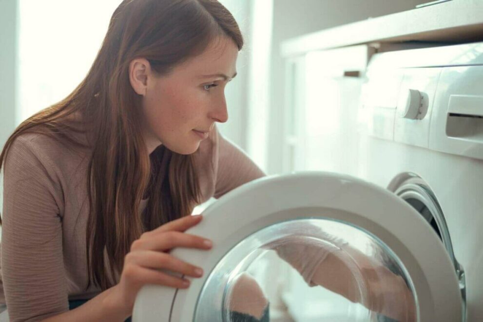 Frau reinigt Doppeldecke mit Waschmaschine