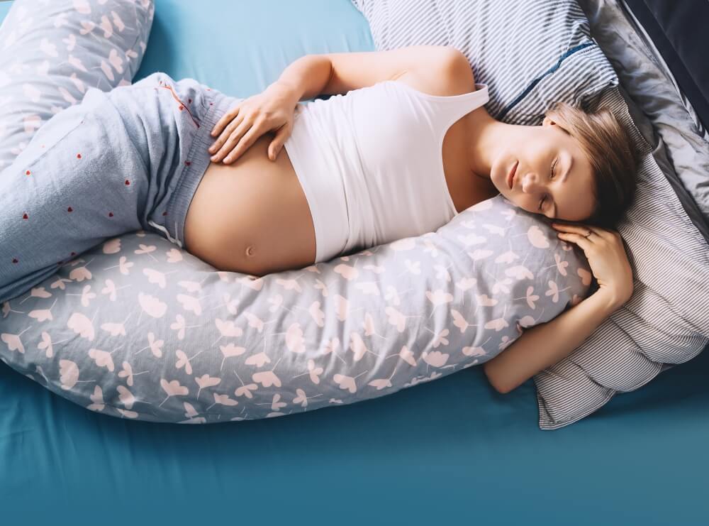 Schwangere schläft mit Unterstützung von Seitenschläferkissen