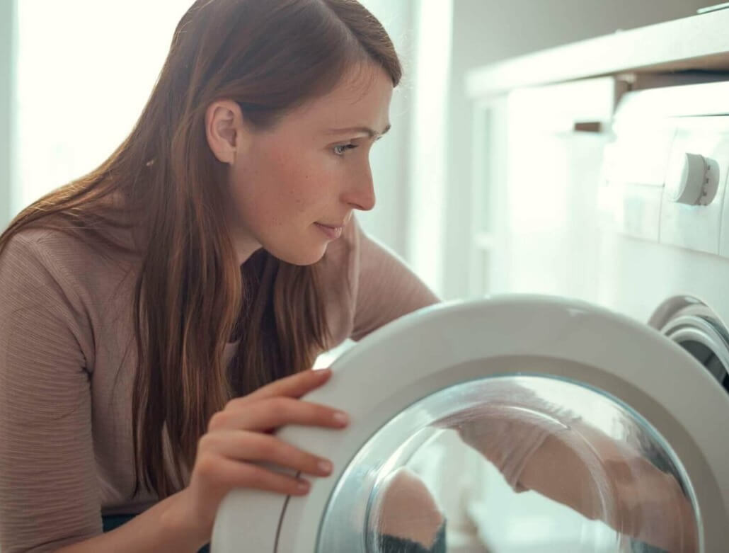 Hirsekissen waschen - Frau vor Waschmaschine